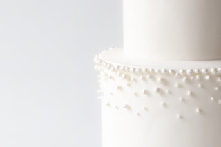 White cake with pearl embellishments on a white background