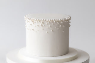 White cake with pearl embellishments on a white background