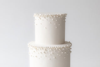 White cake with pearl-like decorations on a light gray background