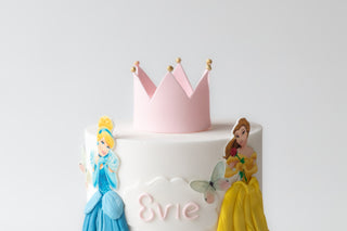 Cake with princess figures and a pink crown on a white background