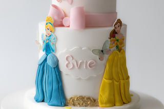 Cake with princess figures and the name 'Evie' on a white background