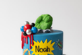 Colorful cake with a green character and 'Noah' on a white background